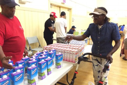 Susan La-Rose selects milk for her daughters at the food pantry at Catholic Charities' Lt. Joseph P. Kennedy Jr. Community Center in Harlem as volunteer Aubrey Woods looks on.