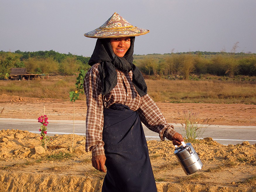 A woman in Myanmar walks home from work. At home the unpaid half of her workday begins, hauling firewood and water for hours to prepare dinner for the family. Markus Kostner/World Bank